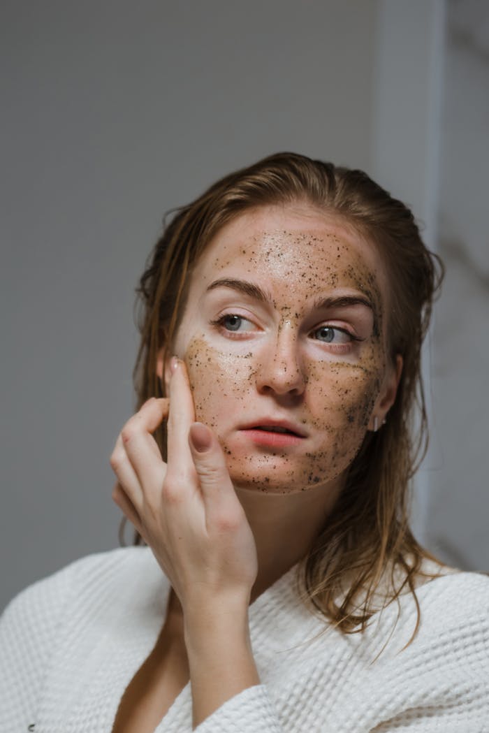 Young woman applying a natural coffee scrub to her face as part of her skincare routine.